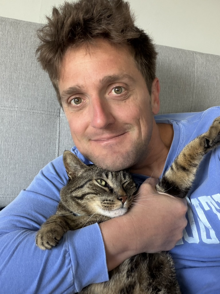 J.J. hugging Baxter the cat on the couch